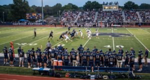 How Many Players Are on a High School Football Team? High school football players on the field during a game, with teammates and coaches watching from the sideline