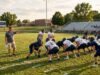 How Long Does the High School Football Season Last? High school football players in full pads practicing on a grass field during the preseason season.