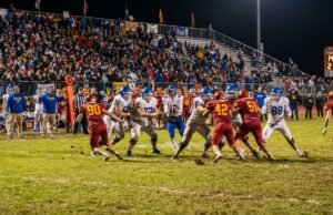 How Many Kids Play High School Football in the US? High school football players competing under Friday night stadium lights in front of packed bleachers in the United States.