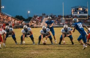 How Many Quarters Are in a High School Football Game? Full Breakdown High school football players lined up at the line of scrimmage under Friday night lights with the scoreboard clock visible