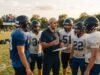 How does one become a high school football coach? A high school football coach with a clipboard instructing players during practice on a grass field